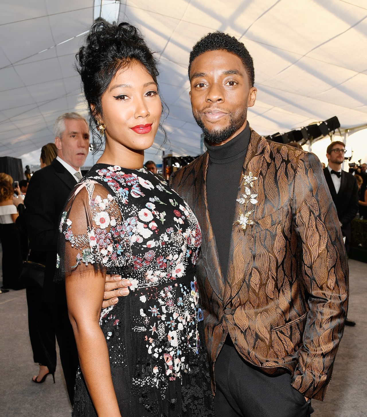 Woman in long dress and man in suit pose.