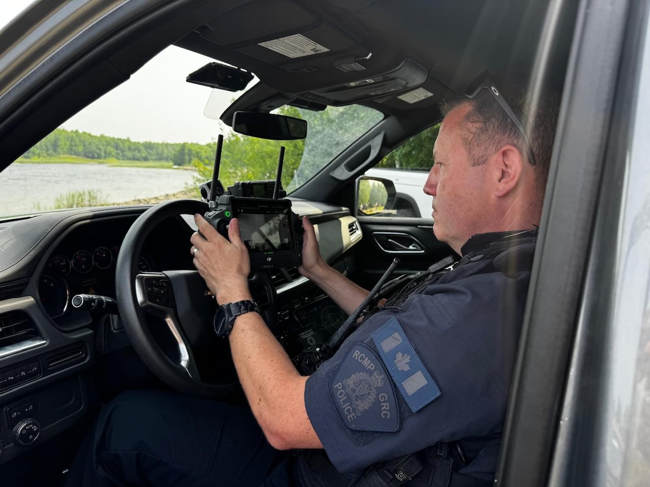 An RCMP officer pilots a drone from within a cruiser.