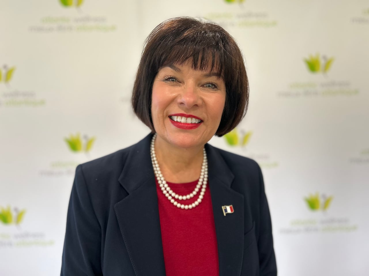 A white woman with short black hair. She is wearing a dark blue blazer.