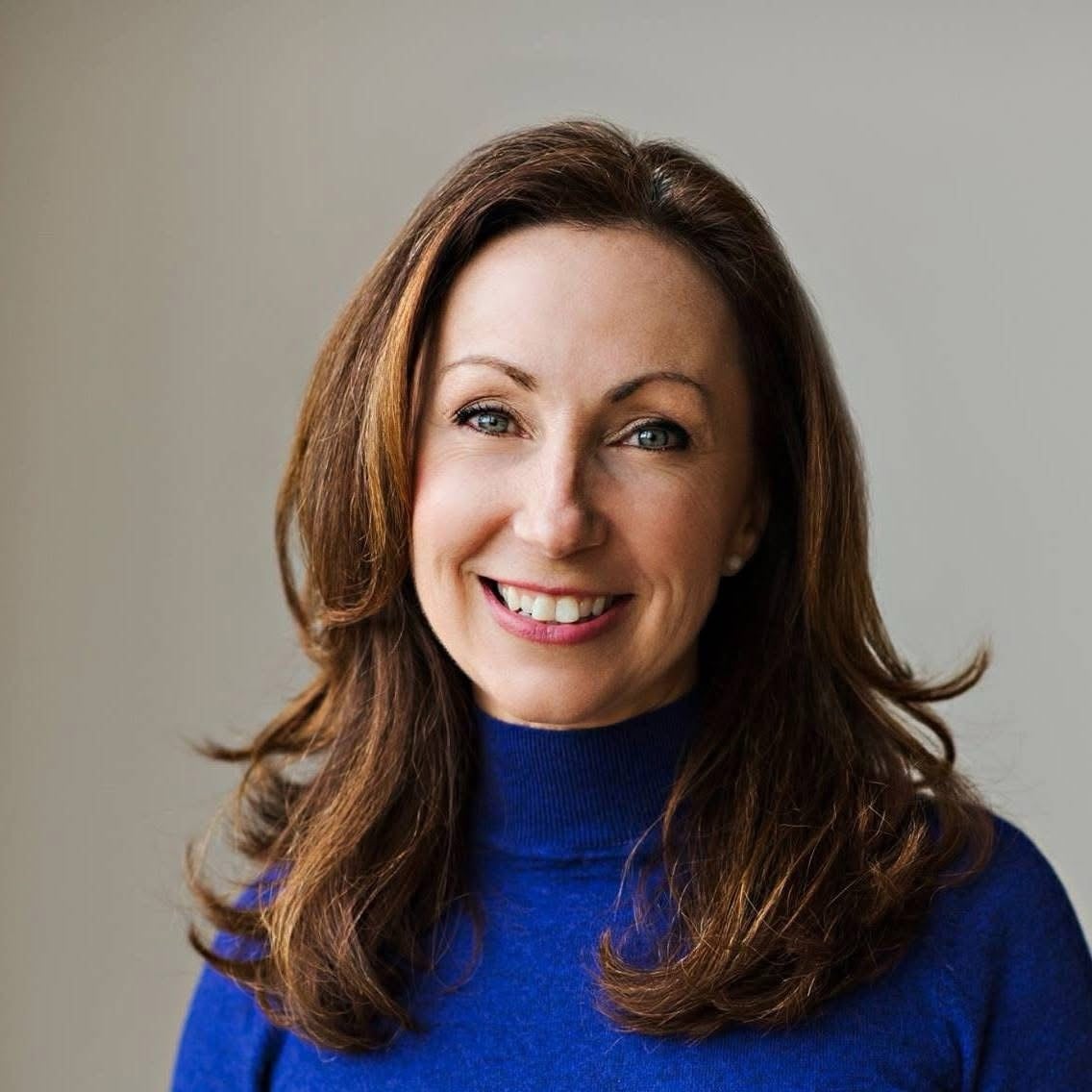 A portrait of a brunette woman in a blue sweater.