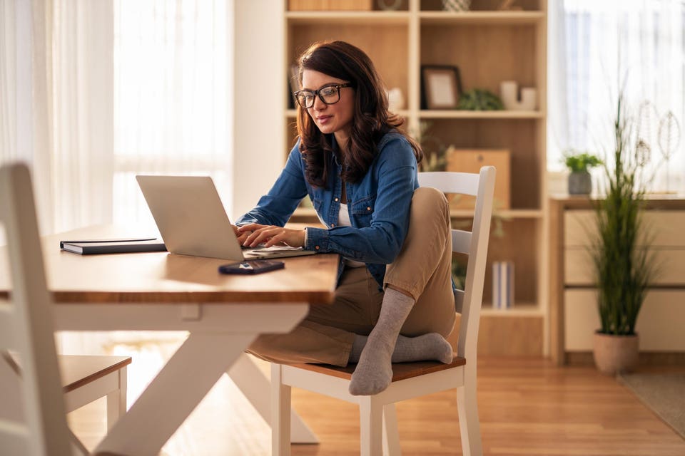 Woman focused on entrepreneurship and job security working on a laptop from home.