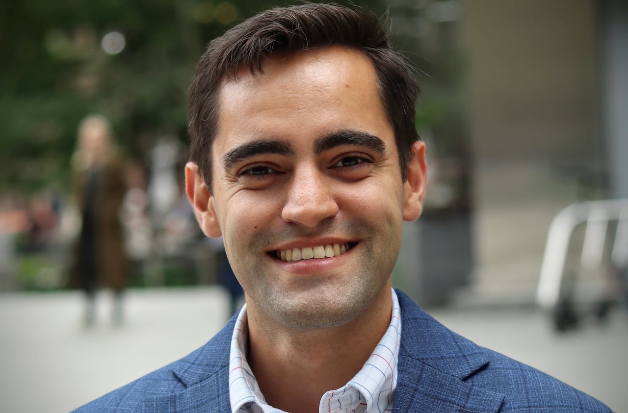 A smiling man, in focus, with brown hair. 