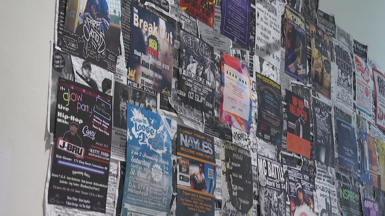 A collage of underground music and event posters completely covering a wall, featuring diverse designs, vibrant graphics, and bold typography.