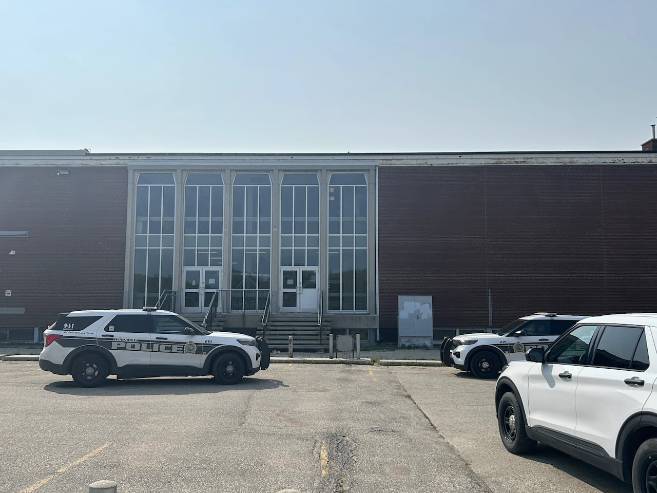 Several police cars parked outside of a high school building.