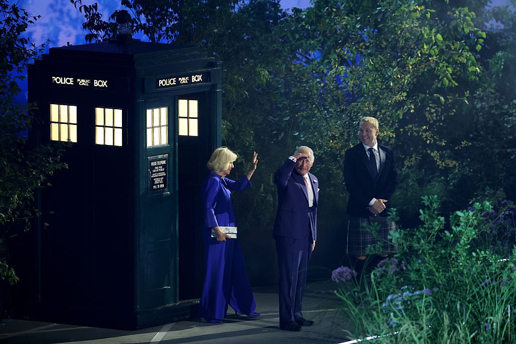 Three people stand in front of a police call box.