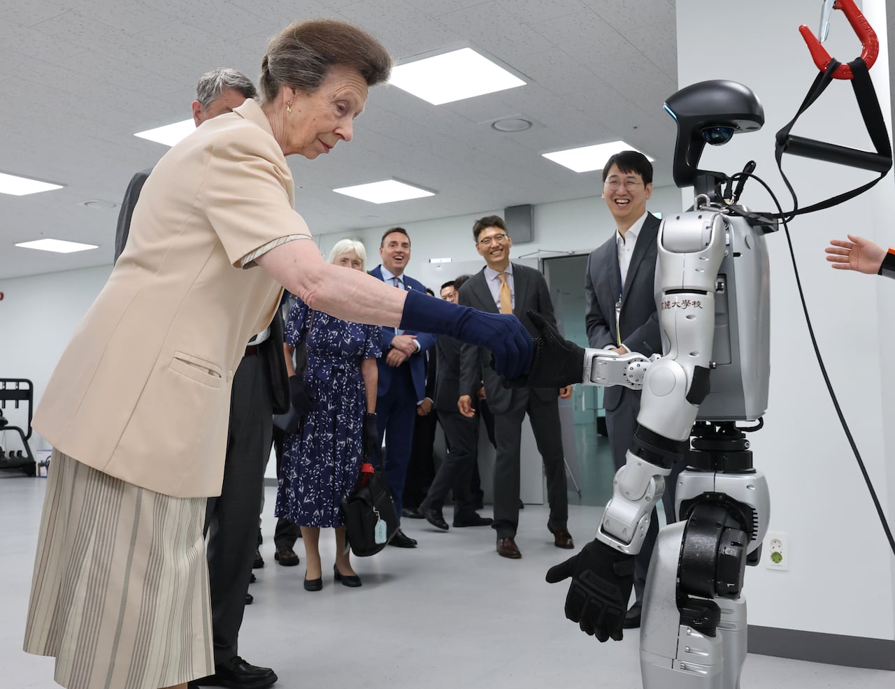 A person shakes hands with a robot as other people look on.