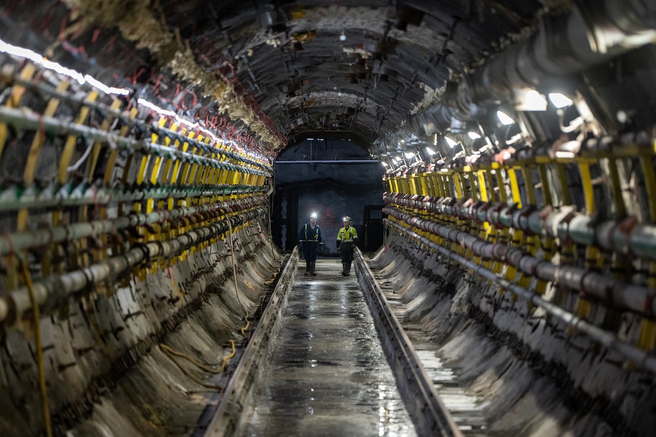 Two people walk along a tunnel in a mine.