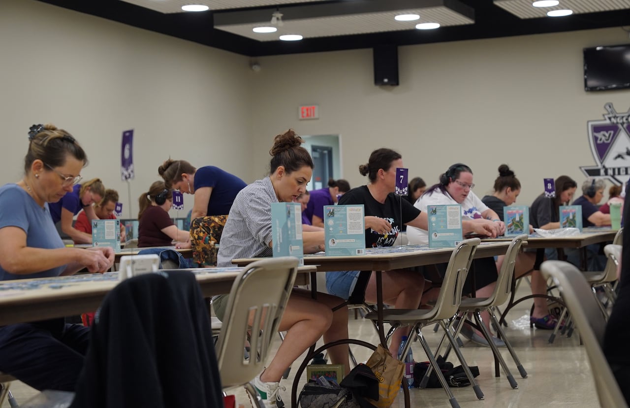 A group of people assembling puzzles in a hall.