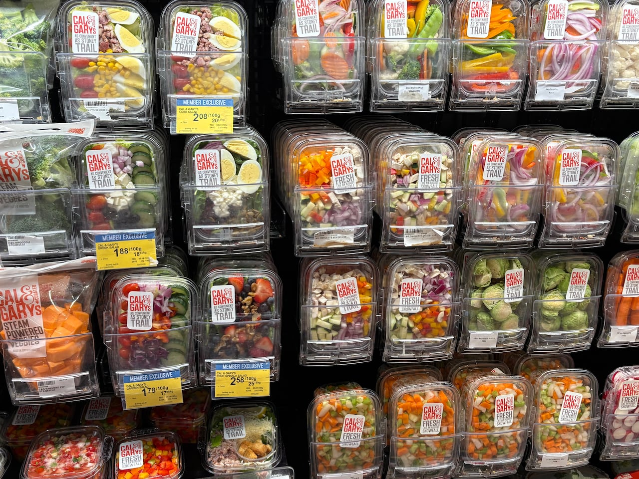 A wall of pre-packaged salads at a grocery store