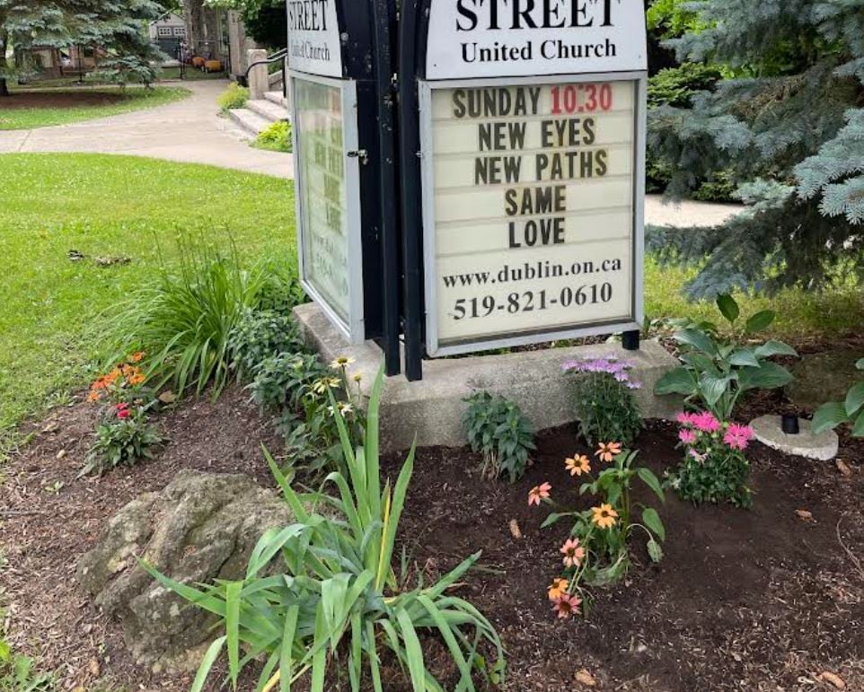 Flower bed in front of a church sign.