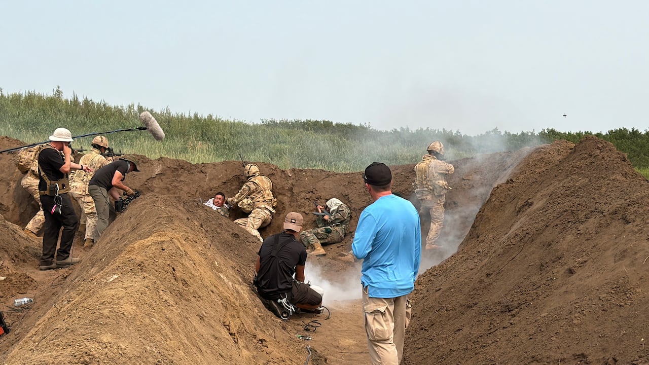 A film production crew and men dressed in Canadian and Afghan military uniforms.