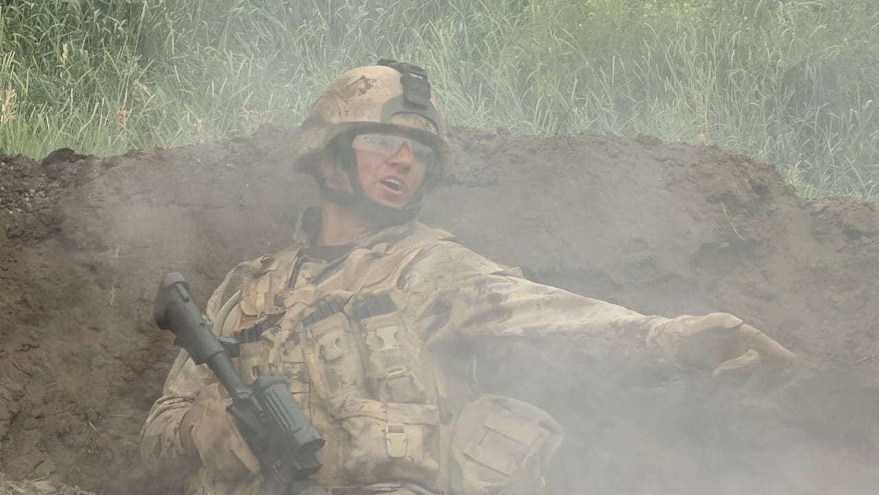 Marshall Williams dressed in a Canadian military uniform and holding a gun while smoke is covering his face yelling at other soldiers.