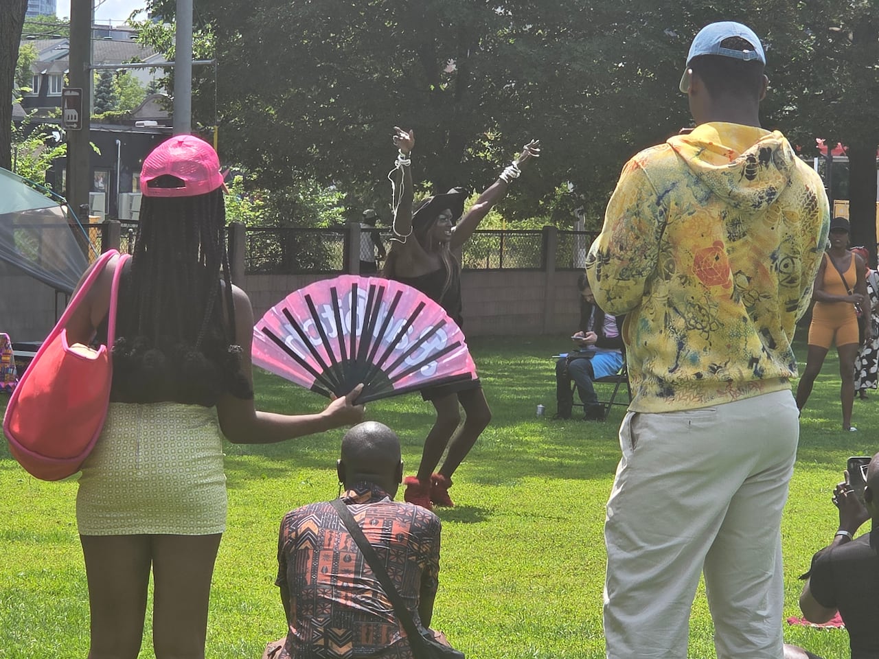 A drag queen is seen performing in a park.