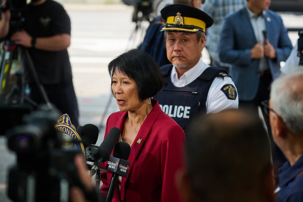 A woman speaks in front of several microphones.
