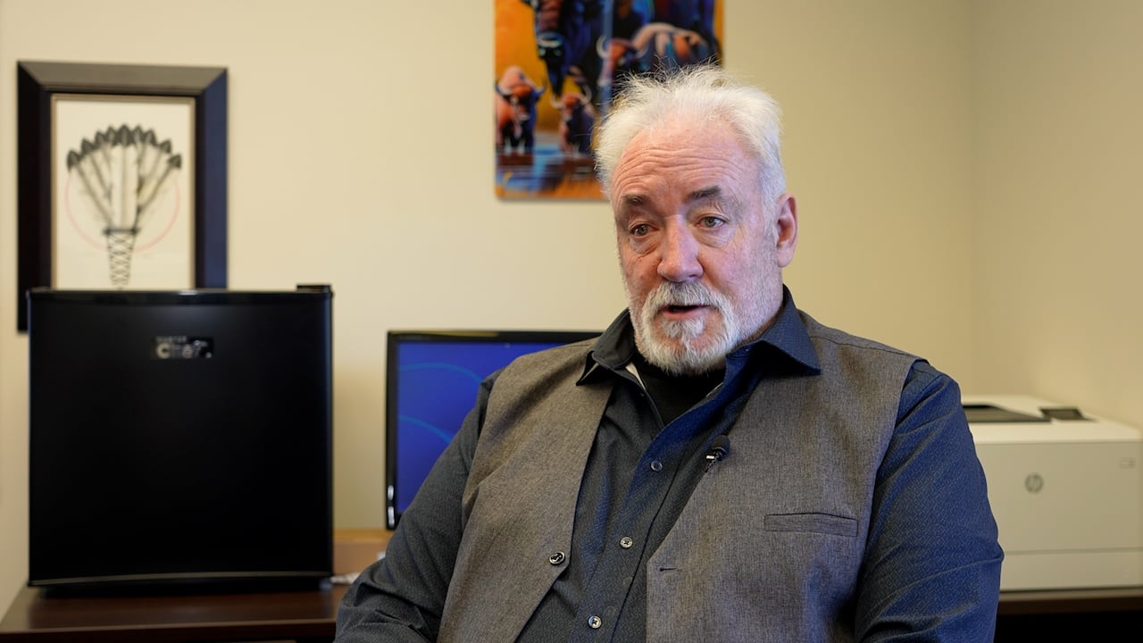 Man talking across, near a computer setup behind him