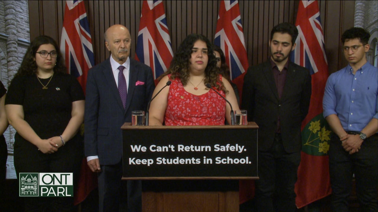 A girl stands at a podium in front of four other people at Queen's Park.