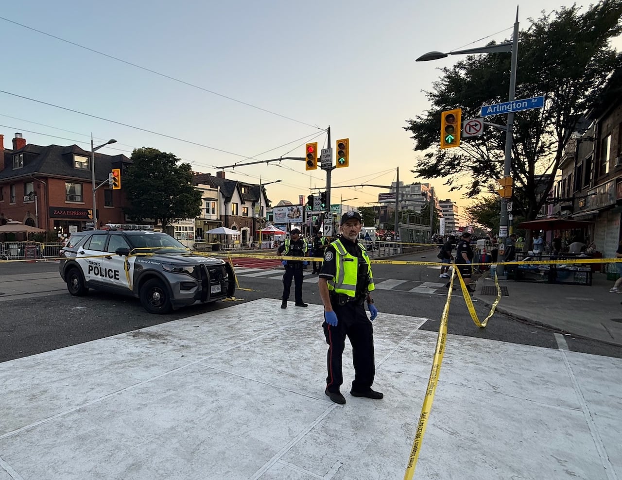 Police stand behind a taped off intersection.