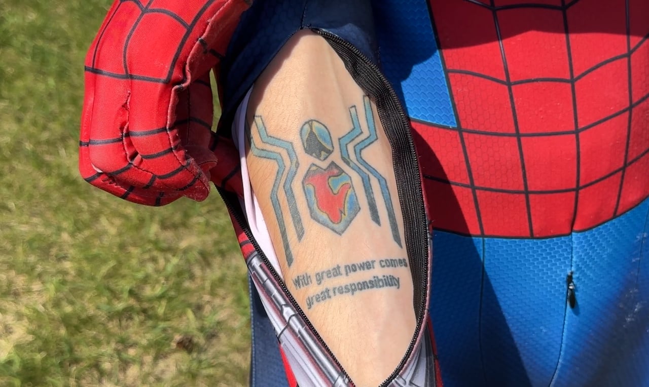 An arm with a blue and red tattoo that says with 'great power comes great responsibility'.