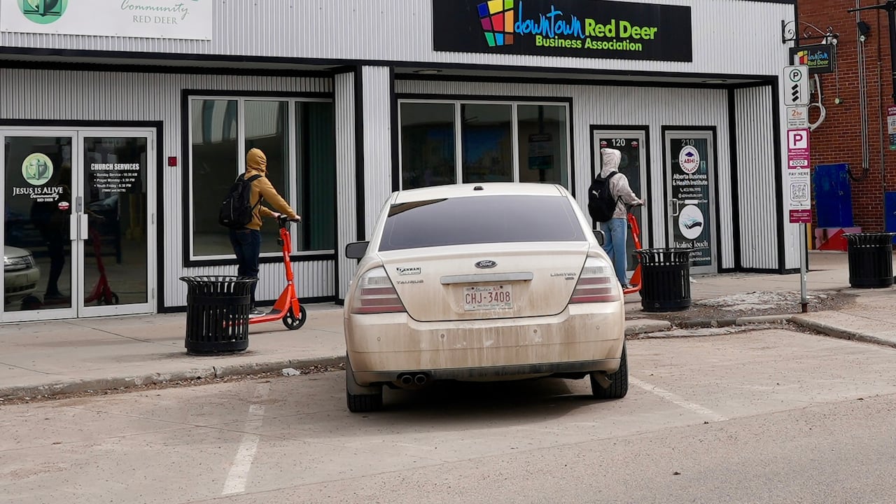 Two people ride e-scooters in downtown Red Deer.