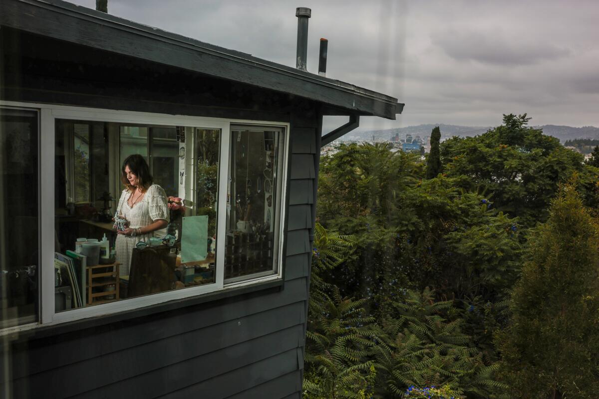 Bayouth stands in her home studio, as seen through an adjacent bedroom window.
