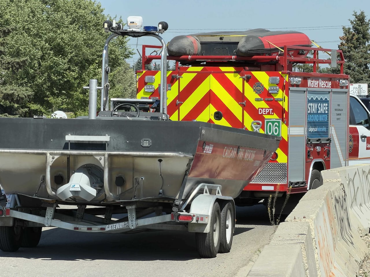 A red and yellow emergency vehicle towing a boat.