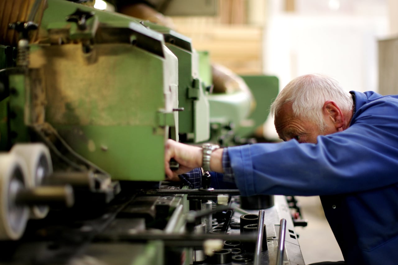 an older man with white hair works on a woodworking machine