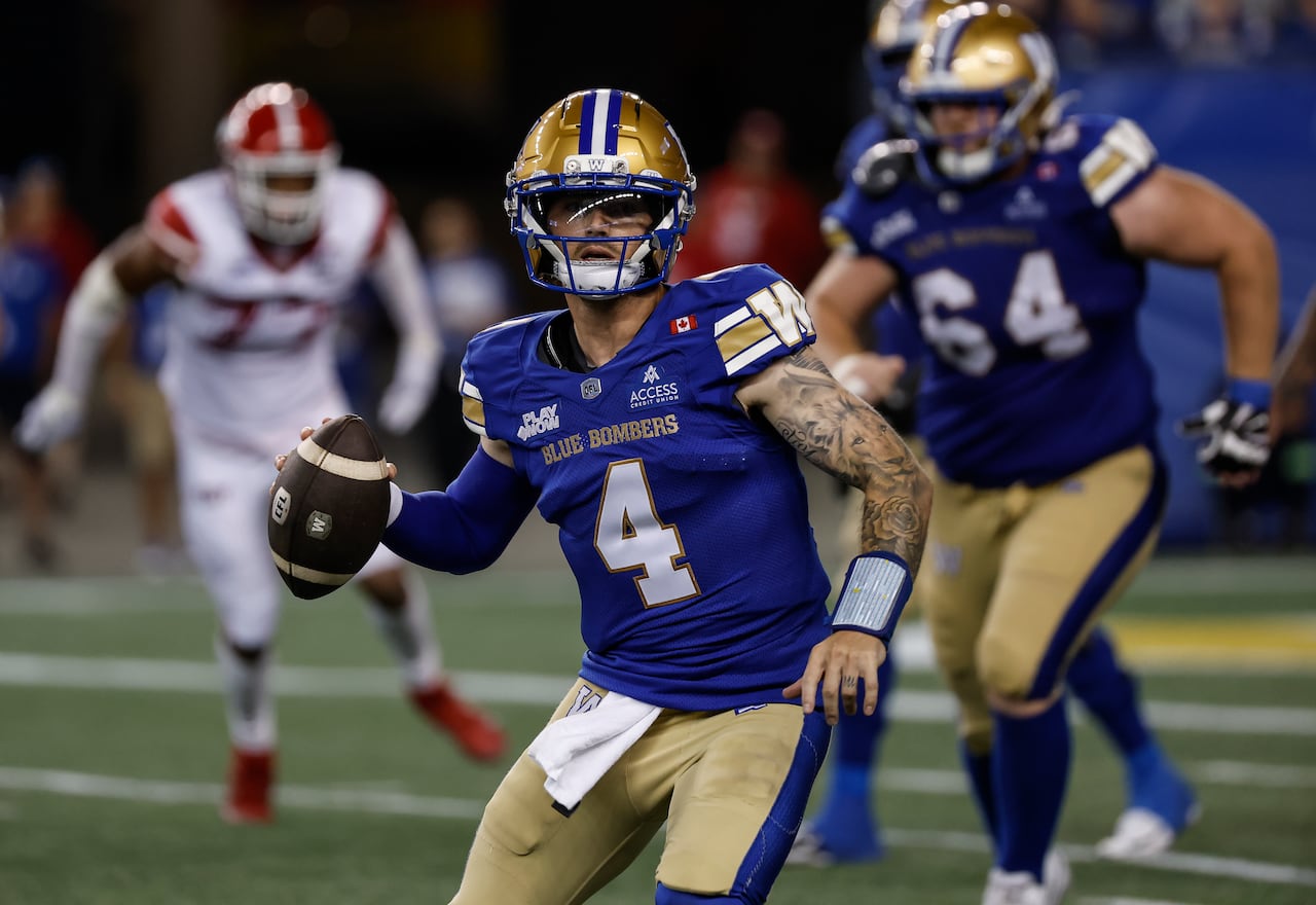 A quarterback in blue and gold holds the ball in his right hand.