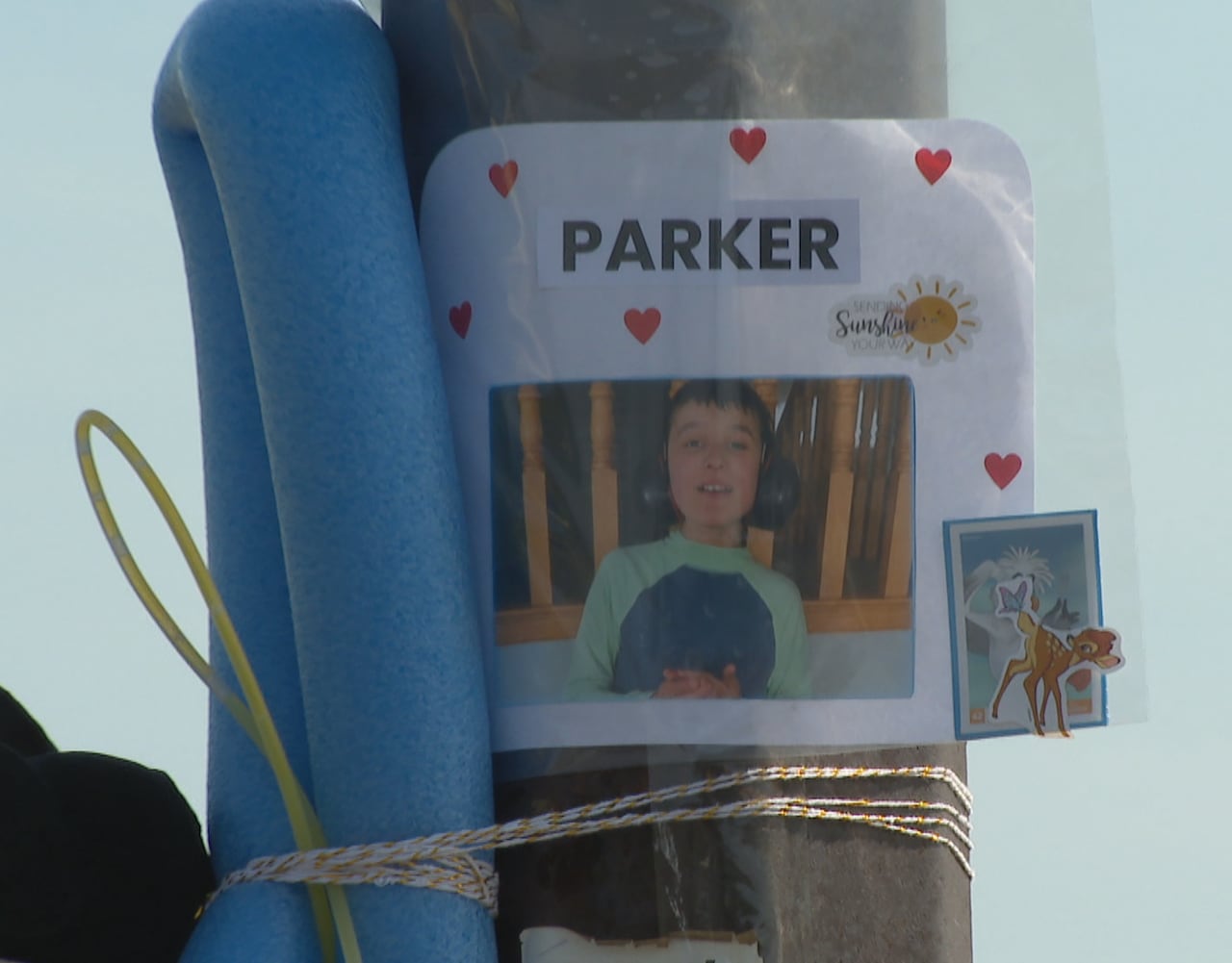 A poster for a missing child is taped to a lamp post alongside children's toys.