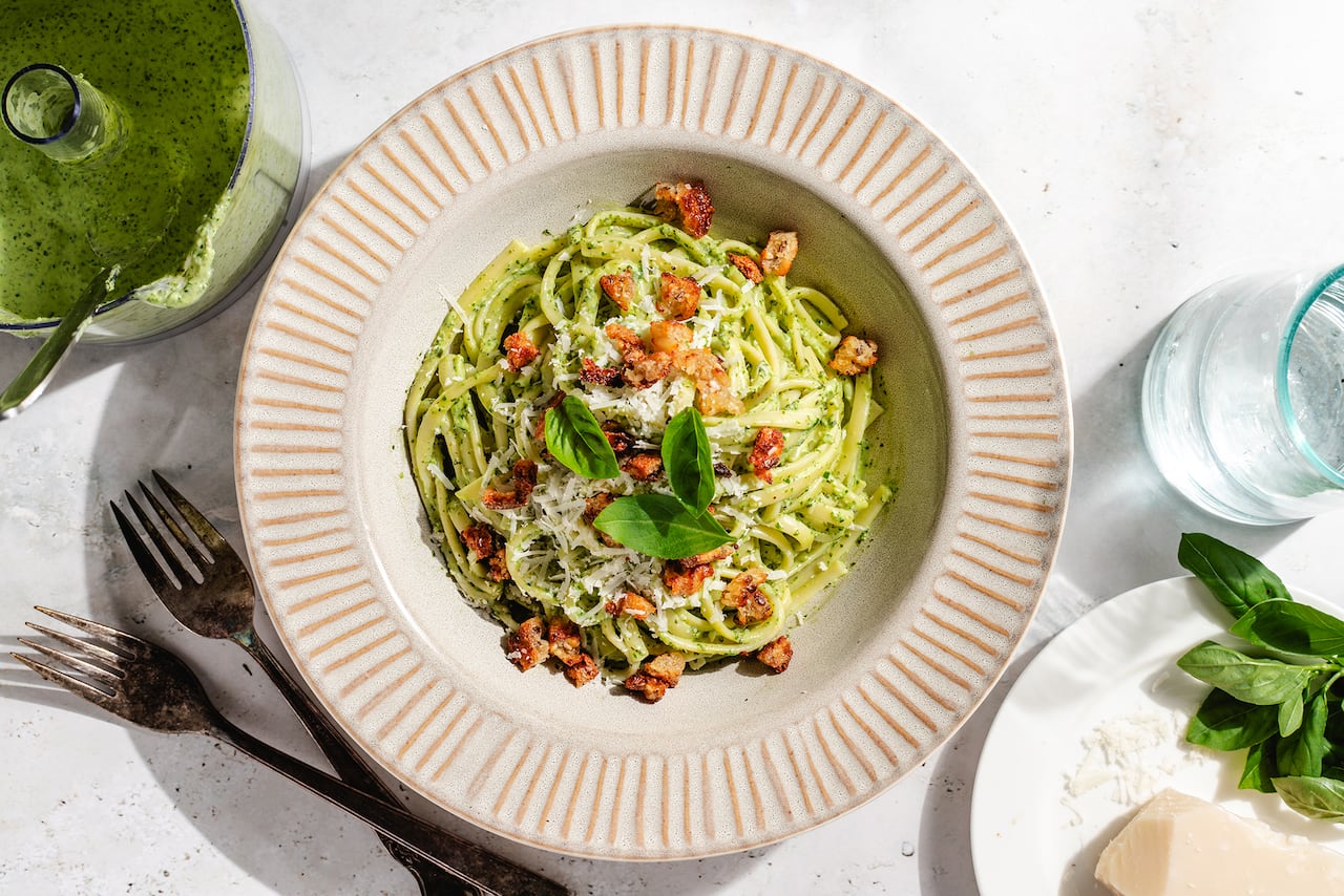 Overhead shot of a bowl of pasta with a green, creamy sauce on it. 
