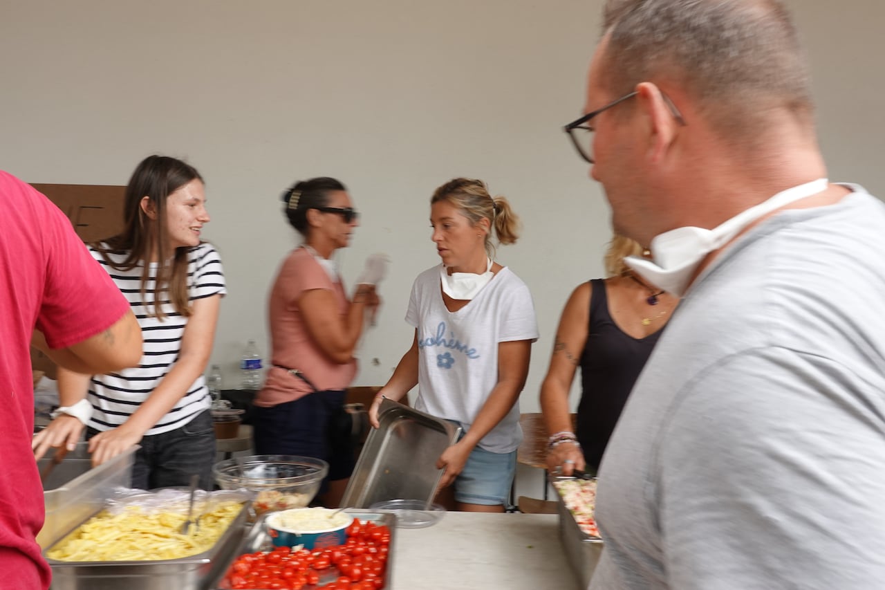 Volunteers serve meals outside a building.