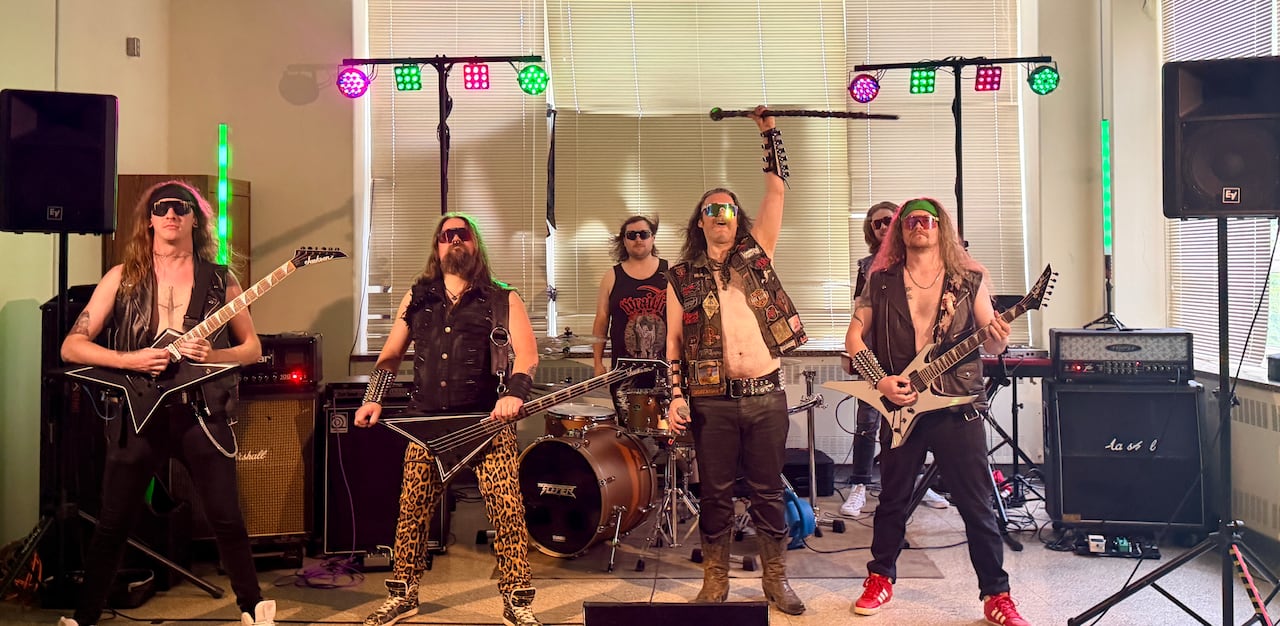 A heavy metal rock band made up of six member stands with their instruments and stage setup.