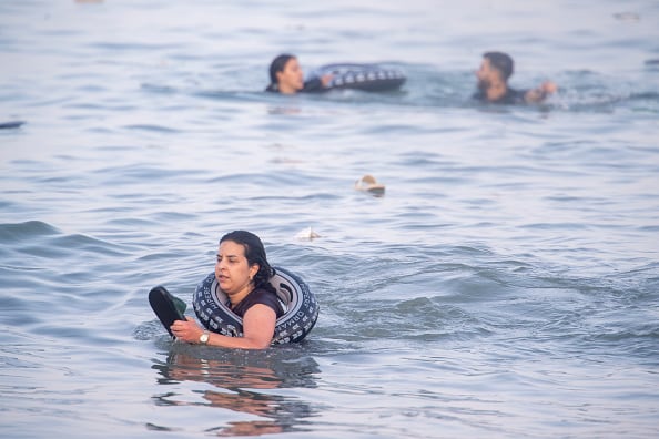 People are shown in the water with flotation devices, like small tires, around them.