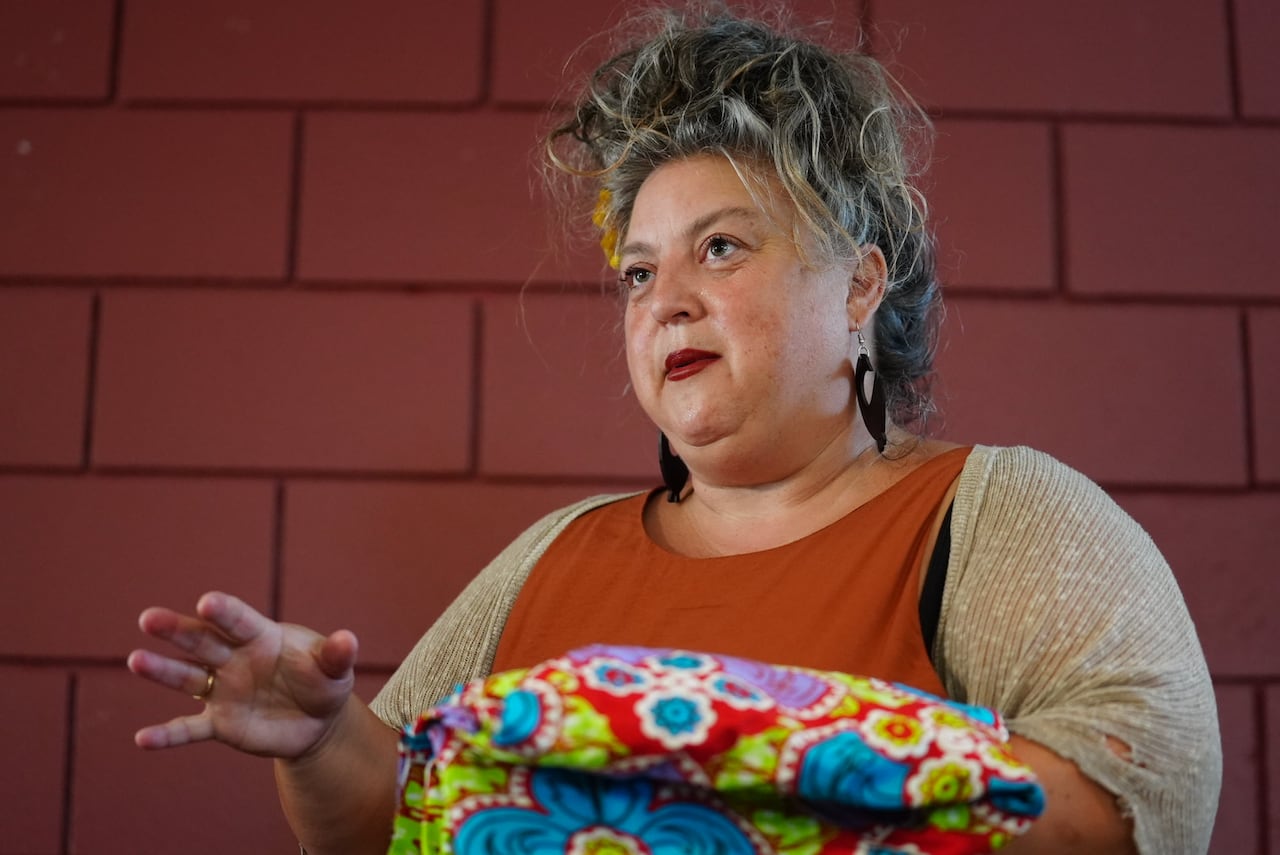 A woman with long grey hair pulled up in a bun looks off to the side of the image.