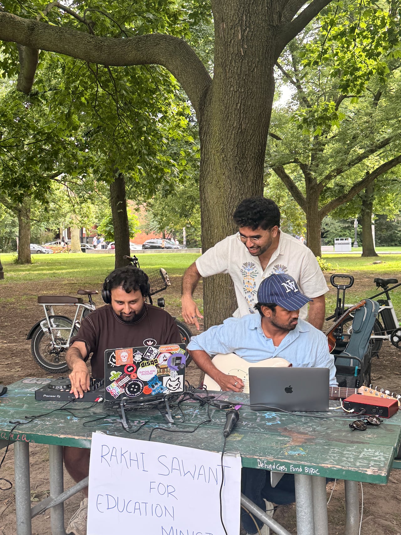 Three South Asian men perform music in a park.