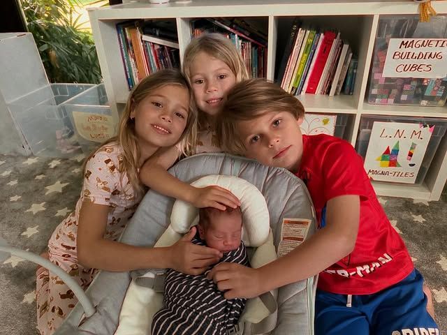 Twins Nicholas and Lucy, 7, and Mary, 5, posed happily next to the new baby
