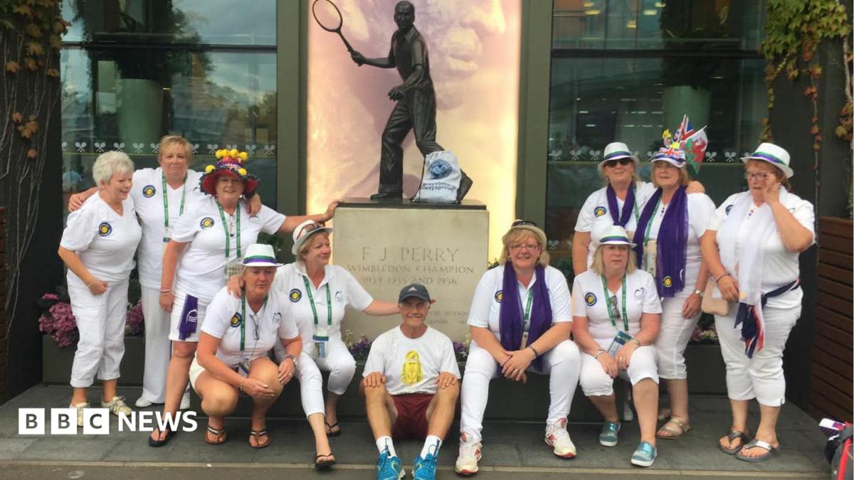 Geoff Hughes is sitting in the middle of a photo in front of a Fred Perry statue surrounded by members of the Andy Murray fan group The Murraynators