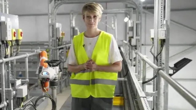 A woman with short, blonde hair wearing a high vis yellow jacket.