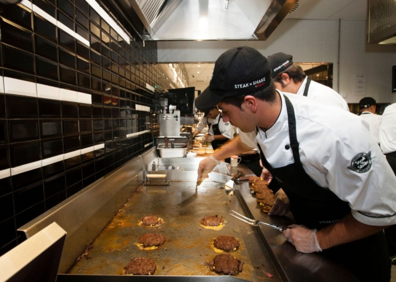 Cooks grilling burgers at Steak 'n Shake. -