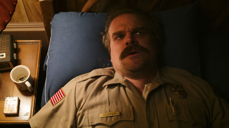 David Harbour's Jim Hopper lays in bed looking worried in Stranger Things