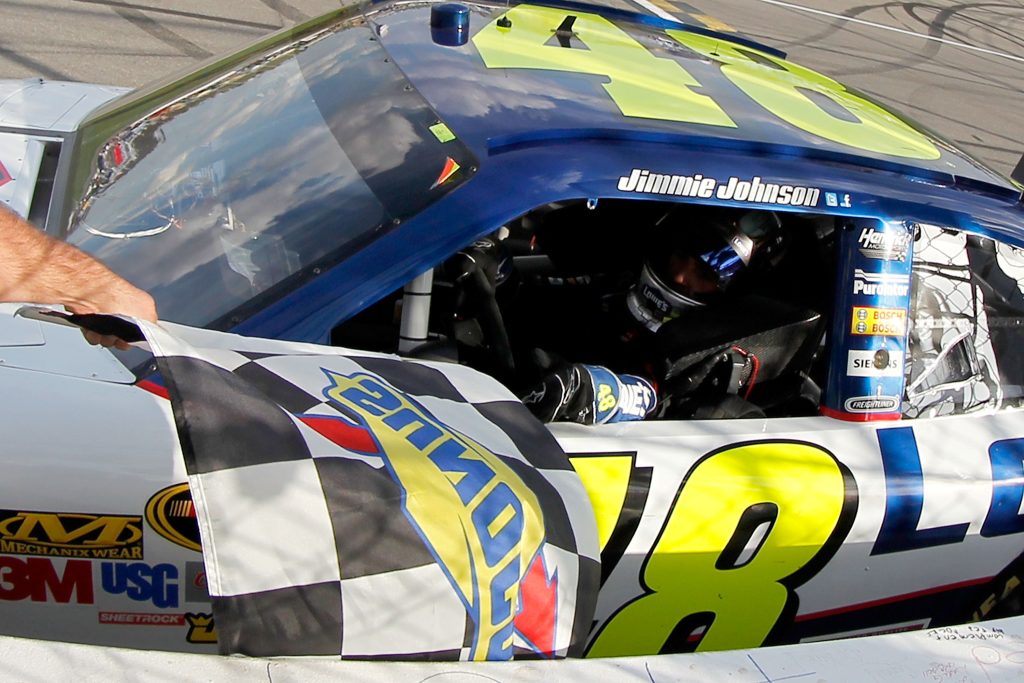 Credit: KANSAS CITY, KS - OCTOBER 09:  Jimmie Johnson, driver of the #48 Lowe's Chevrolet, takes the checkered flag from a NASCAR official after winning the NASCAR Sprint Cup Series Hollywood Casino 400 at Kansas Speedway on October 9, 2011 in Kansas City, Kansas.  (Photo by Todd Warshaw/Getty Images for NASCAR) *** Local Caption *** Jimmie Johnson