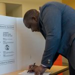 A person voting behind a privacy screen.