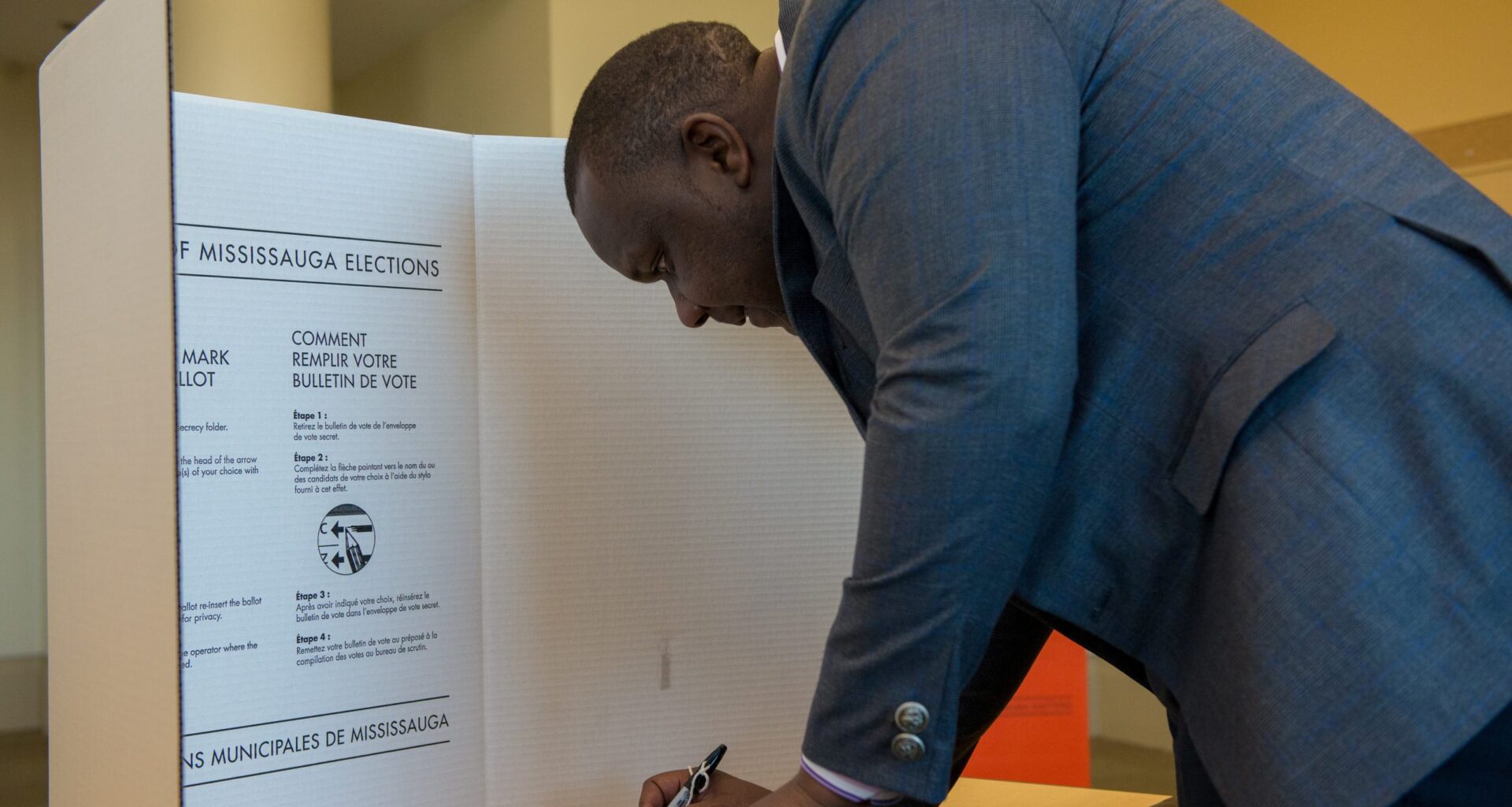 A person behind a privacy screen voting.