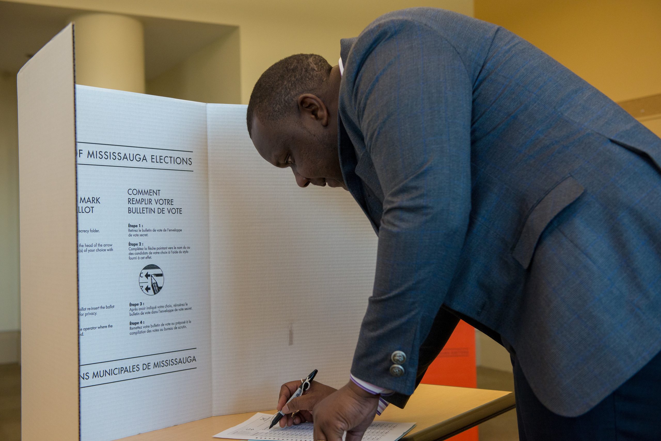 A person behind a privacy screen voting.