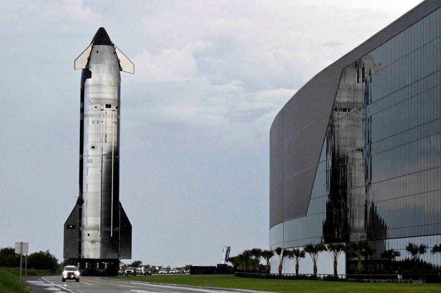 A SpaceX Starship spacecraft rolls out toward its launchpad past the Starbase Manufacturing Facility in August 2025.