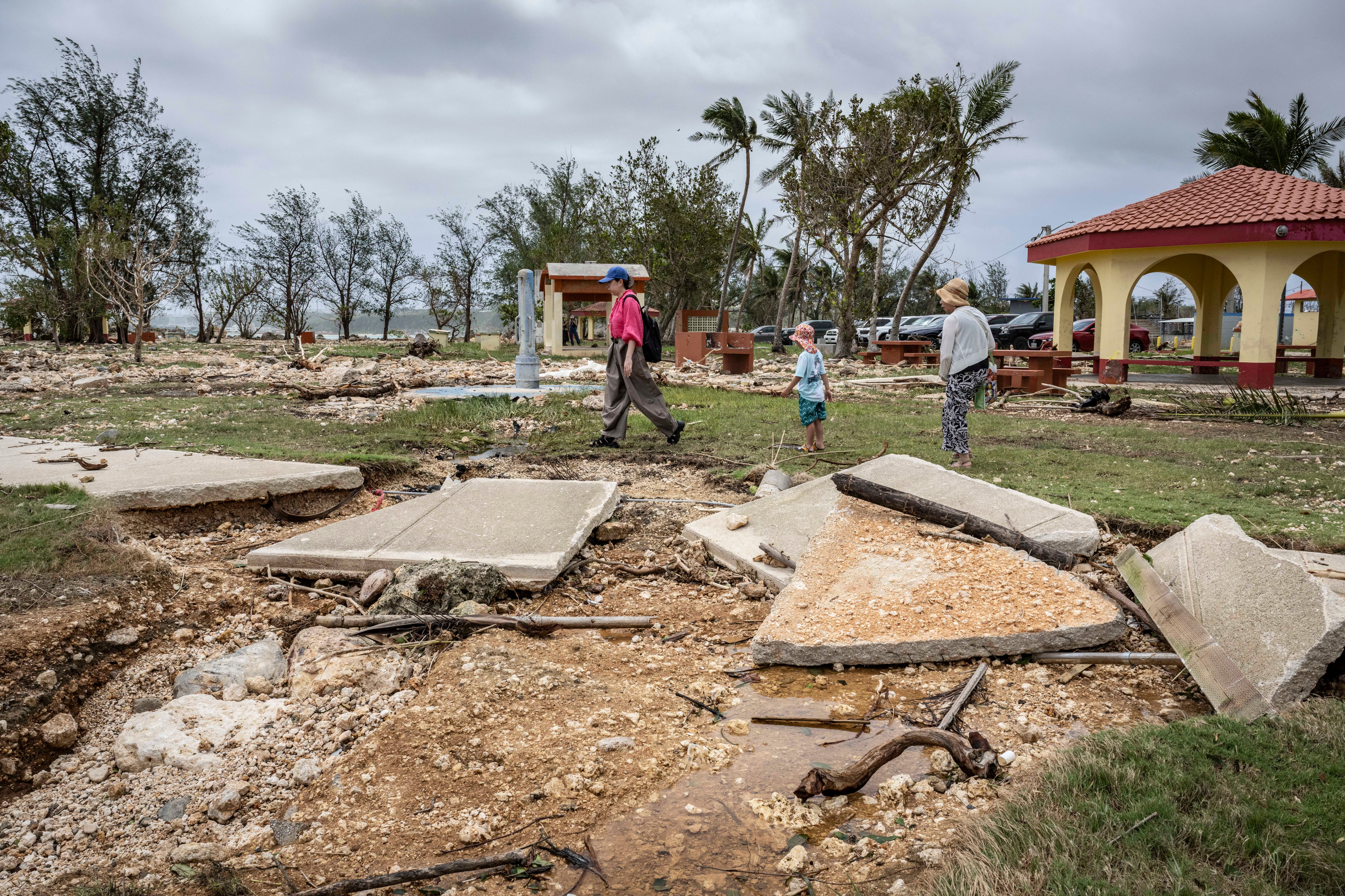 People walk past a damaged walkway at a park in the aftermath of Super Typhoon Bavi in Guam