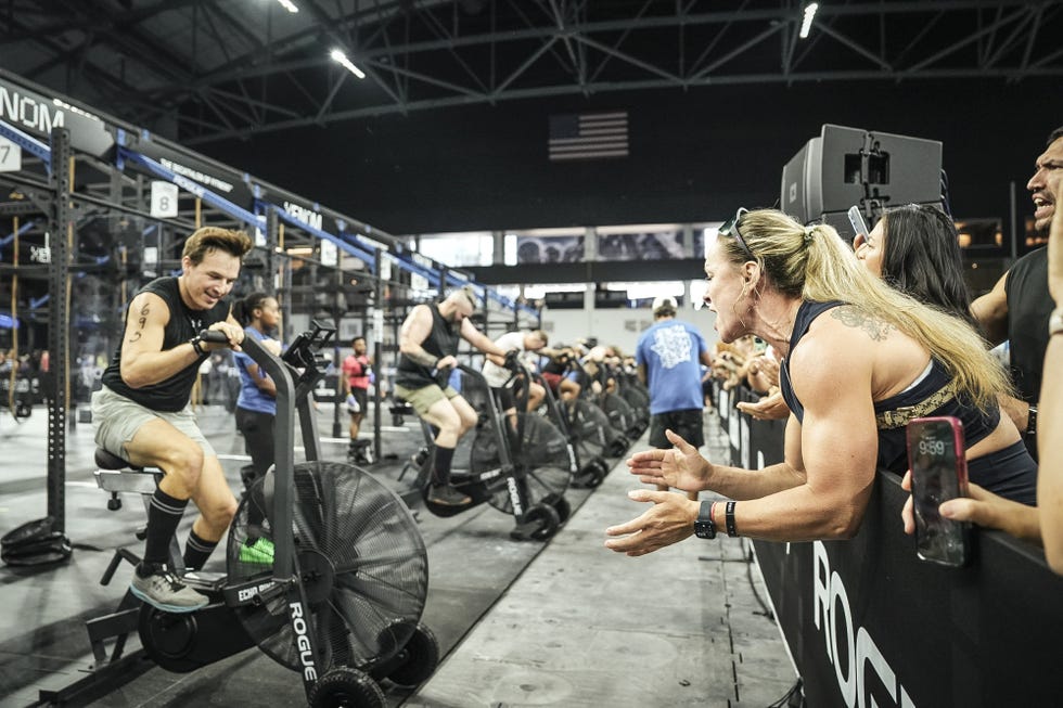 Participants engaging in an intense workout while supporters cheer them on in a competitive fitness event. Participants engaging in an intense workout while supporters cheer them on in a competitive fitness event.