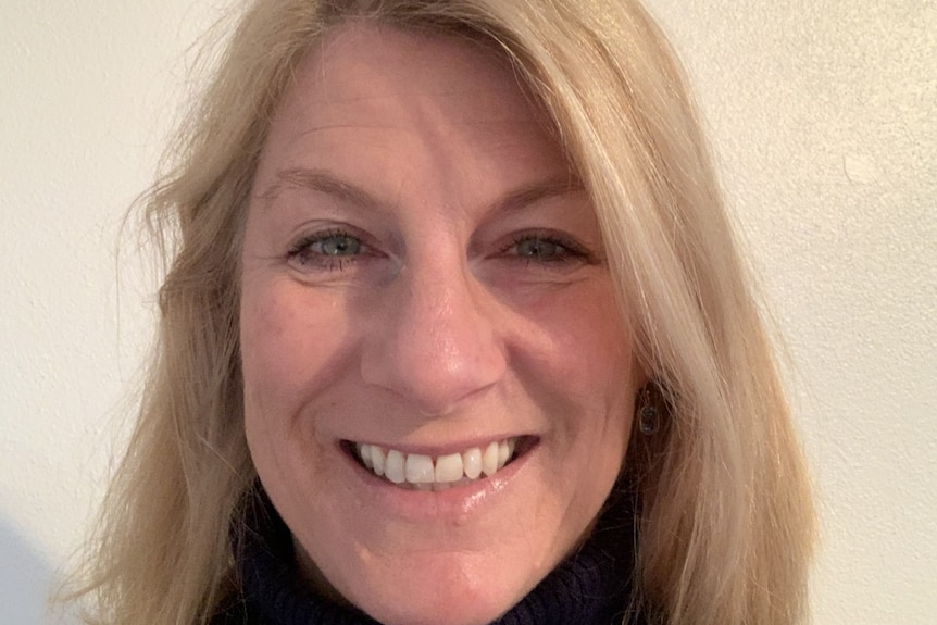 A woman smiles at the camera in a black shirt