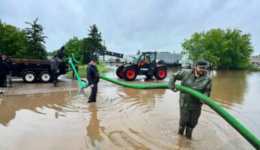 Volunteers standing in floodwater operate large pumps to remove water from flooded homes in Norquay, Saskatchewan.