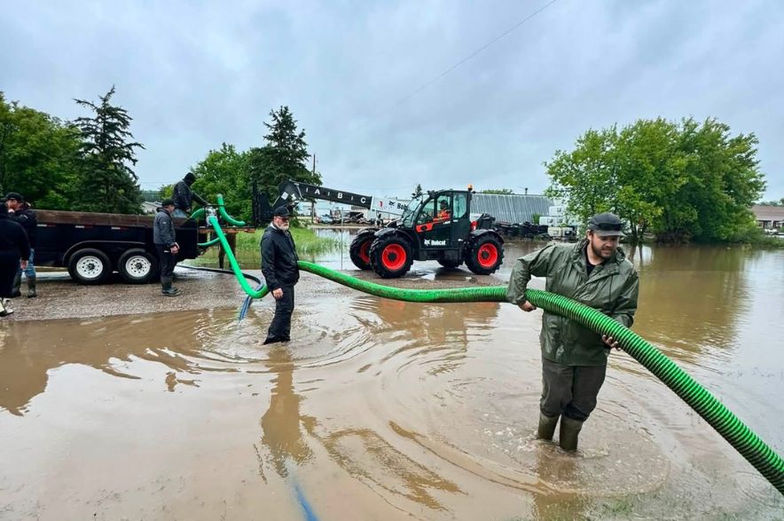 Volunteers standing in floodwater operate large pumps to remove water from flooded homes in Norquay, Saskatchewan.