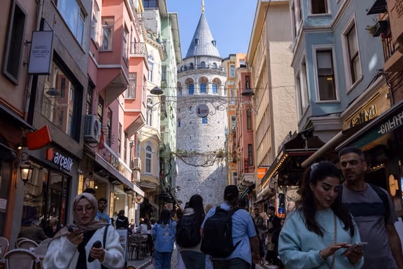 People walk on a small street that leads to the historical Galata Tower in Istanbul.